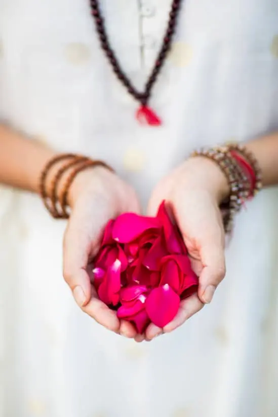 Woman meditating with flower petals in hand.